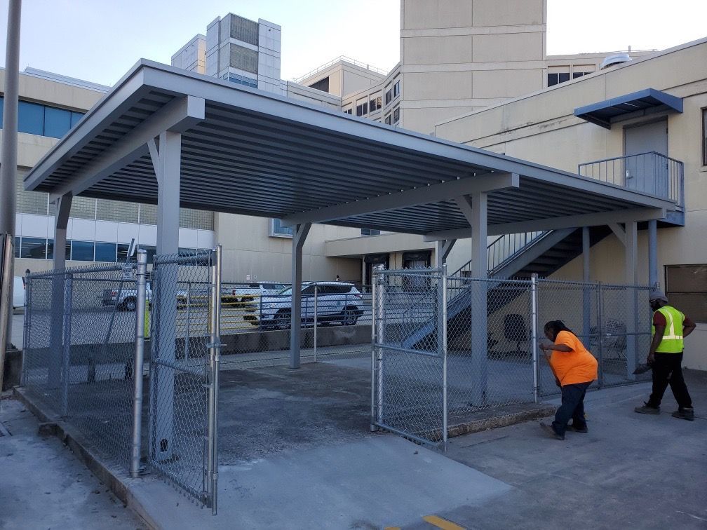 A man is standing on a ladder fixing a sliding gate.