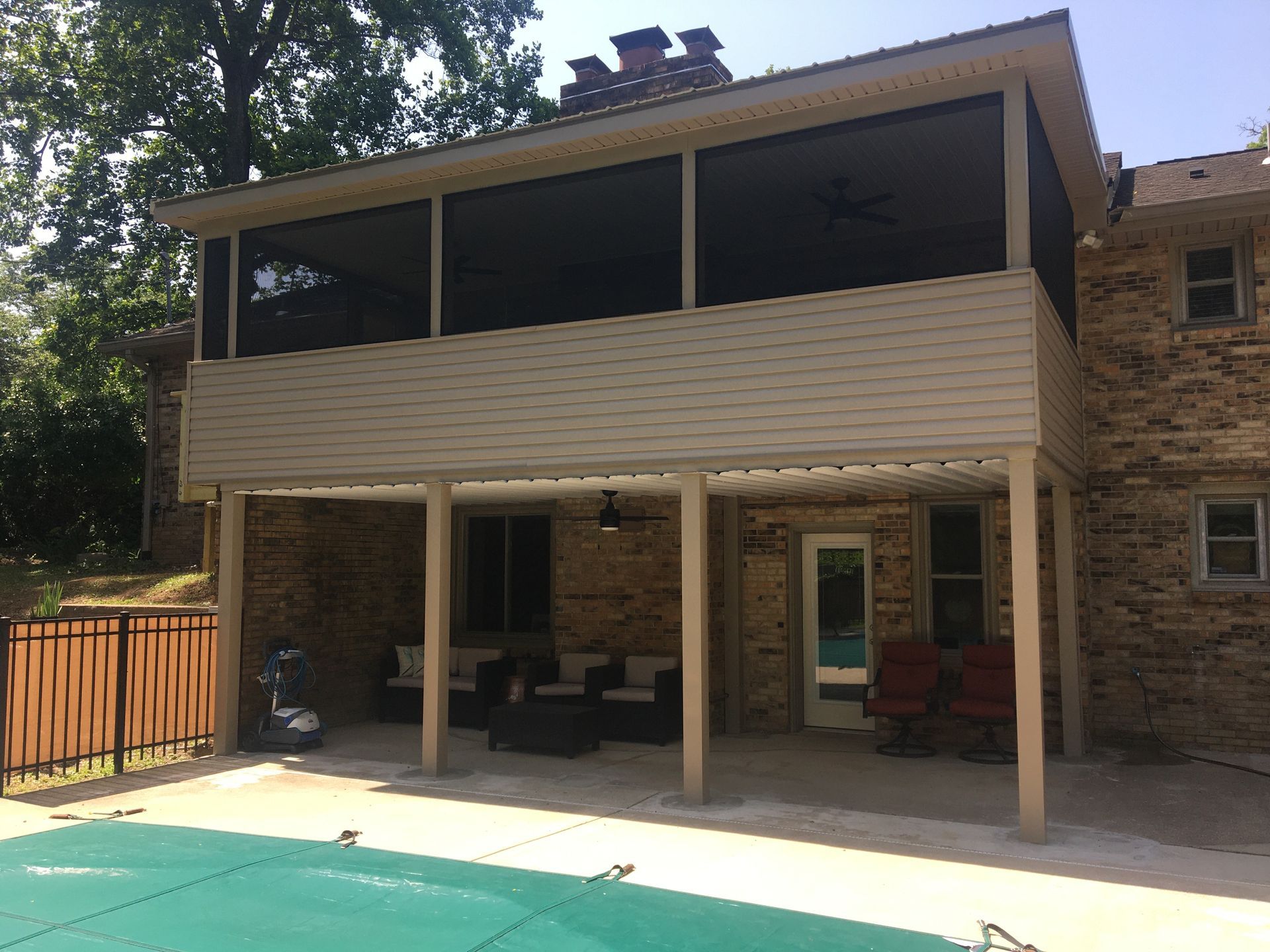 Two-story brick house with a screened-in porch overlooking a pool.