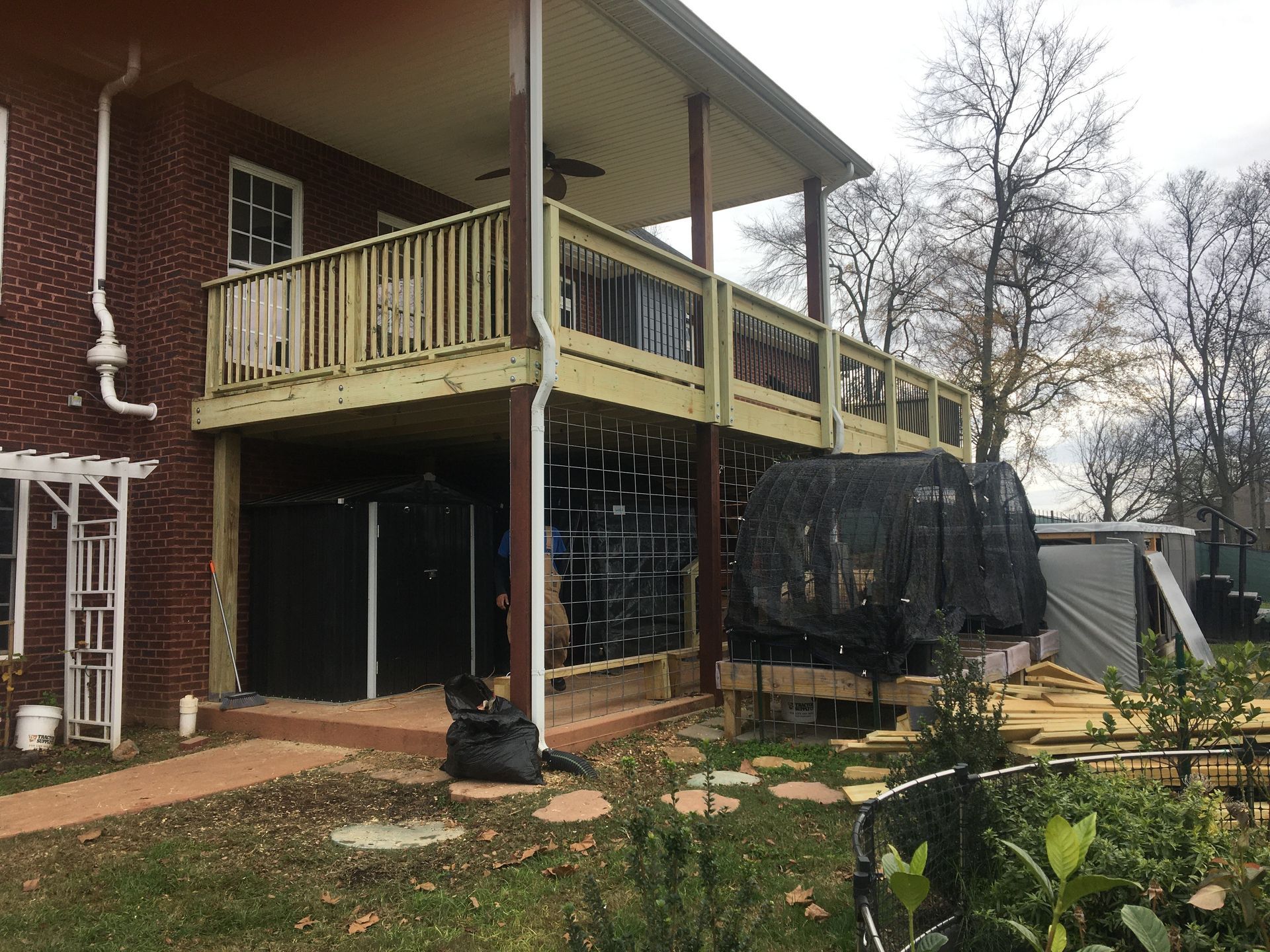 Brick house with a two-story wooden deck. The lower level is partially enclosed with equipment storage.