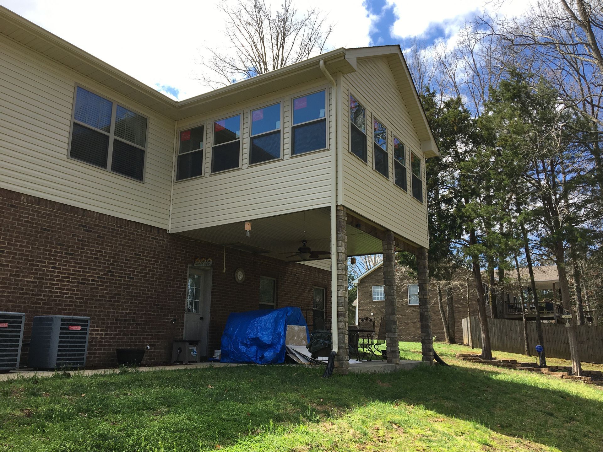 A two-story house with a screened porch, brick and siding exterior, and a grassy backyard.