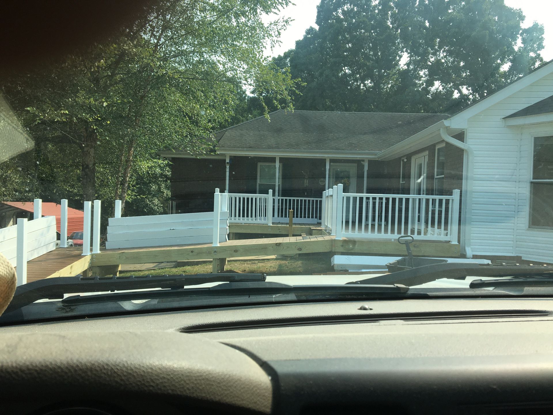 View from a car window of a house with a white deck and railings.