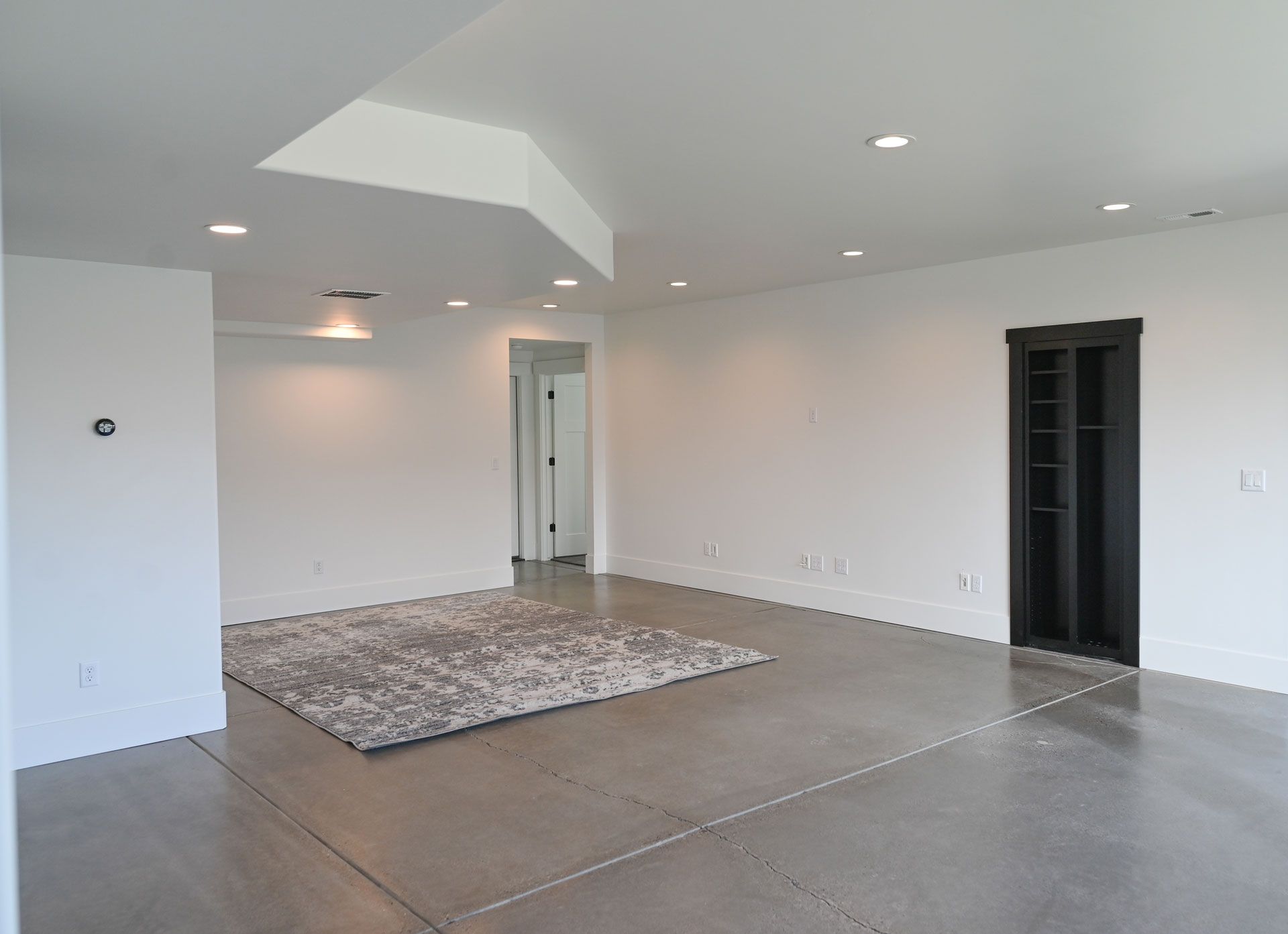 A large empty room with white walls and a rug on the floor.