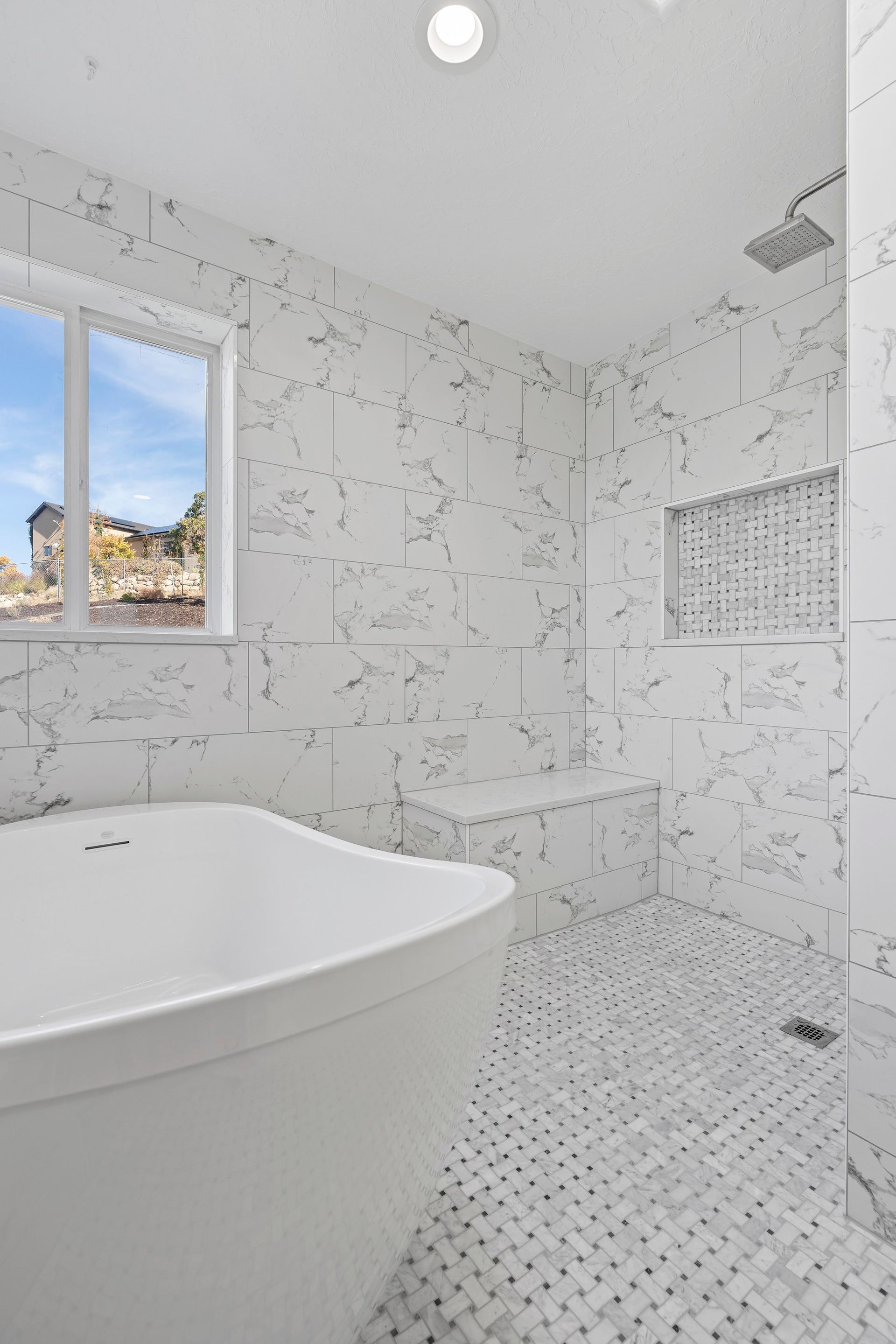 A bathroom with a tub , shower and window.