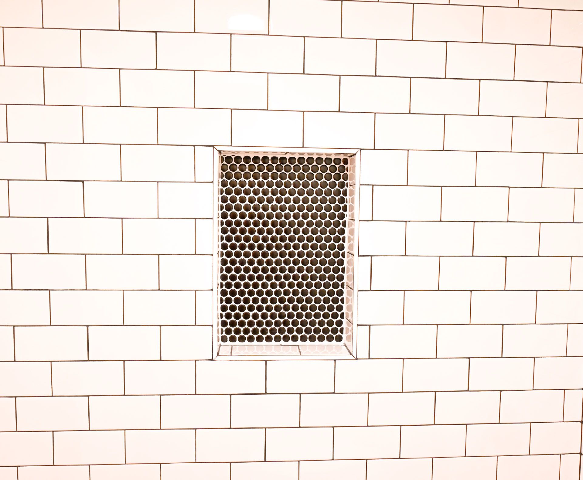 A white brick wall with a small window in the middle