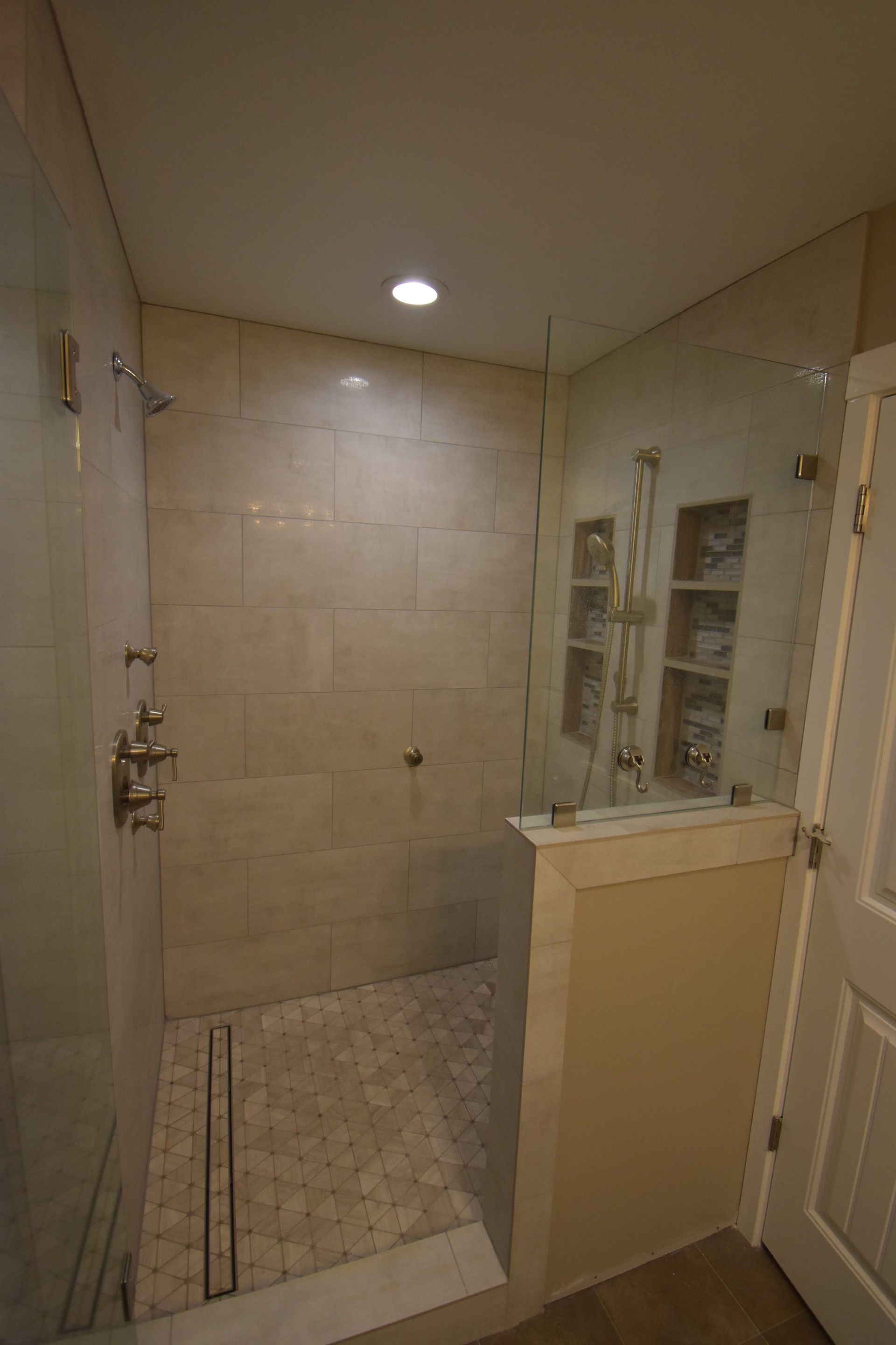 A bathroom with a walk in shower and a glass door.