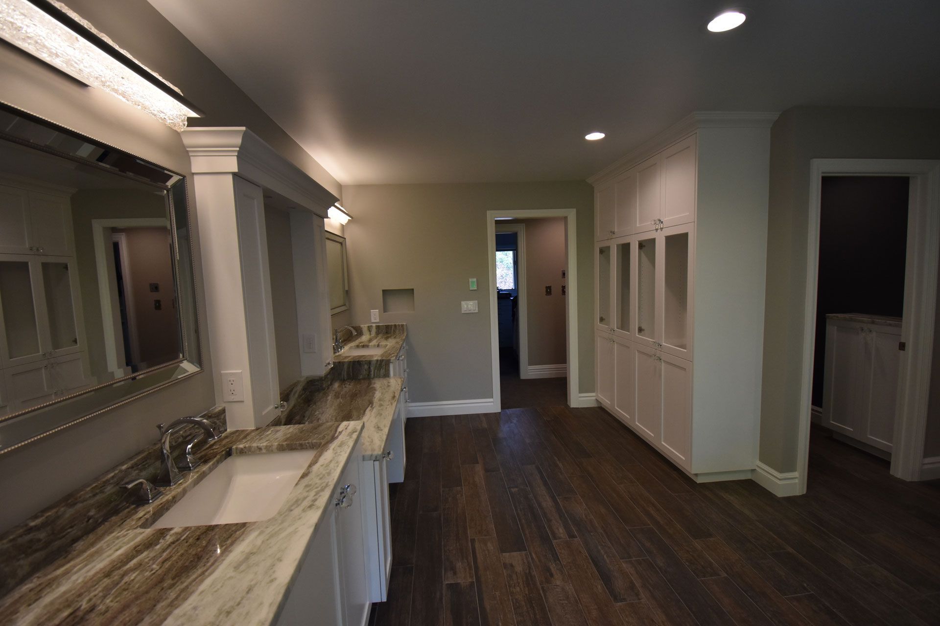 A bathroom with two sinks , a mirror , and hardwood floors.