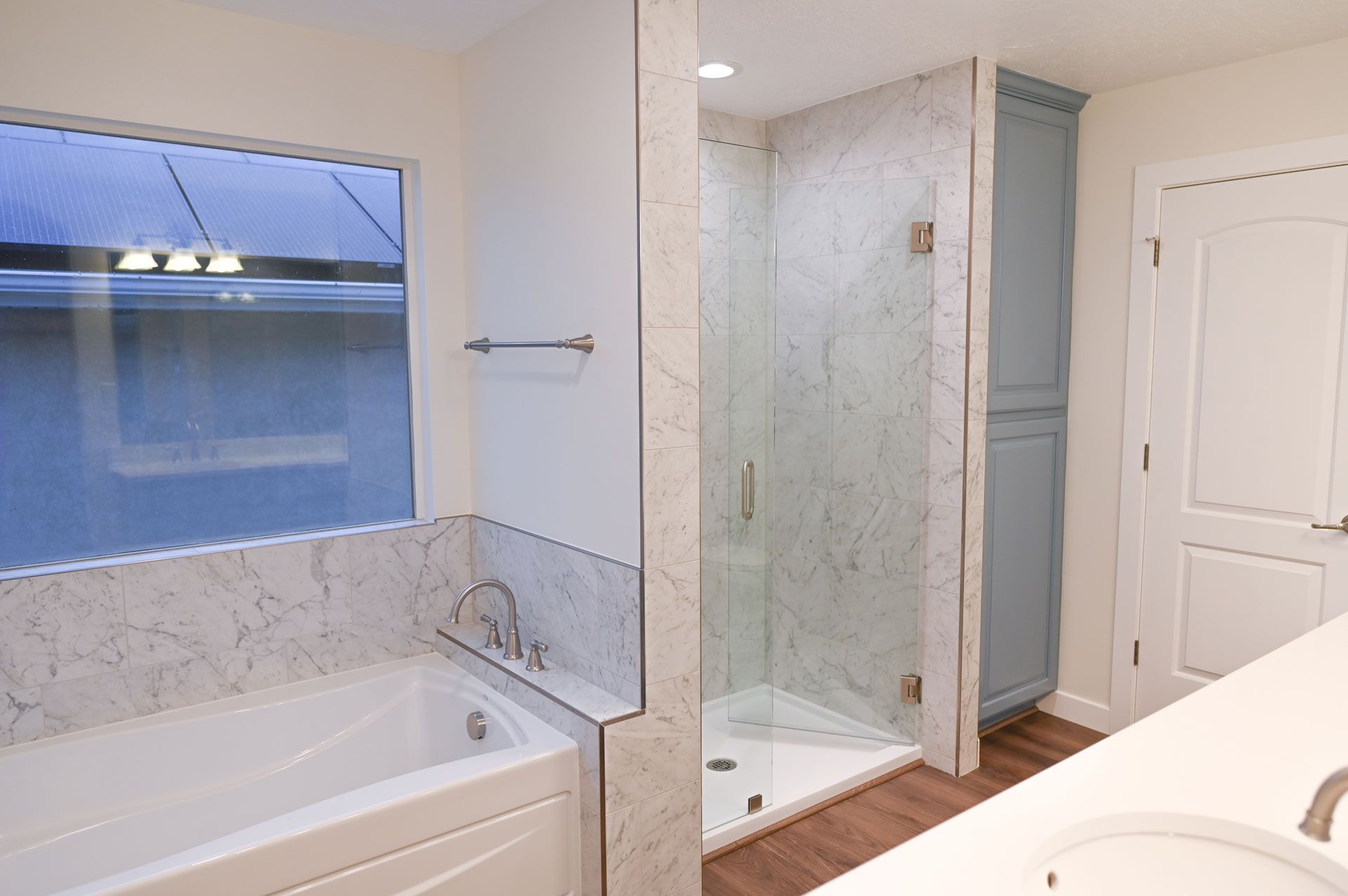 A bathroom with a tub , sink , shower and window.