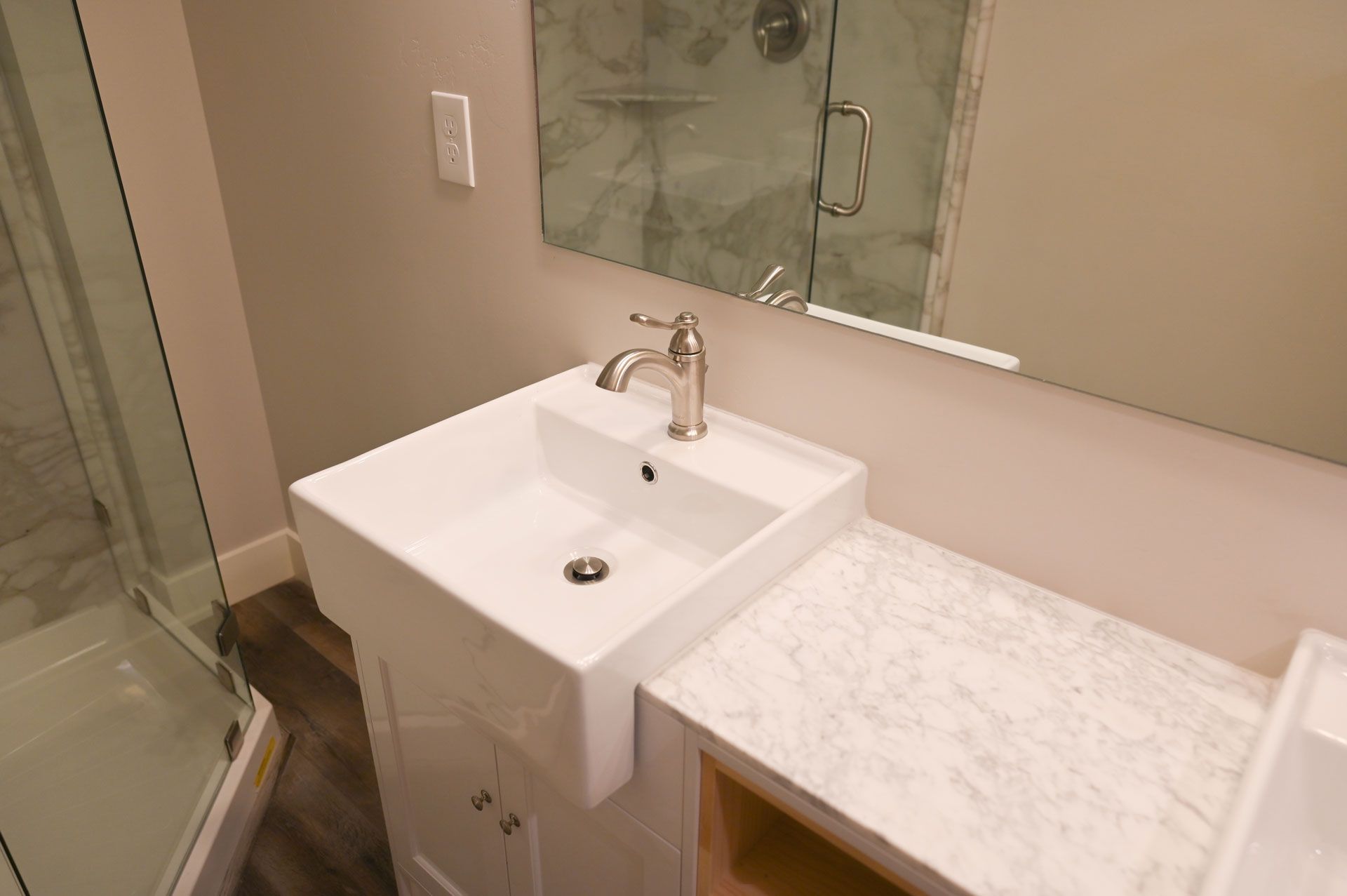 A bathroom with a sink , mirror and shower.