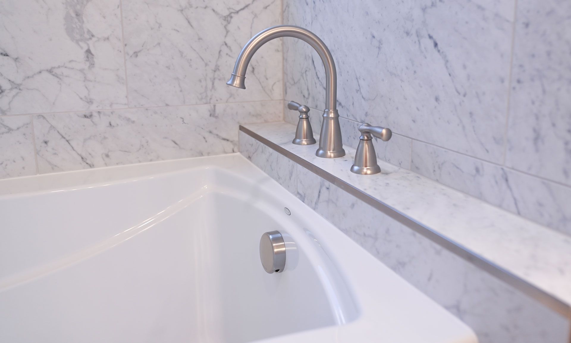 A bathtub with a faucet on the side of it in a bathroom.