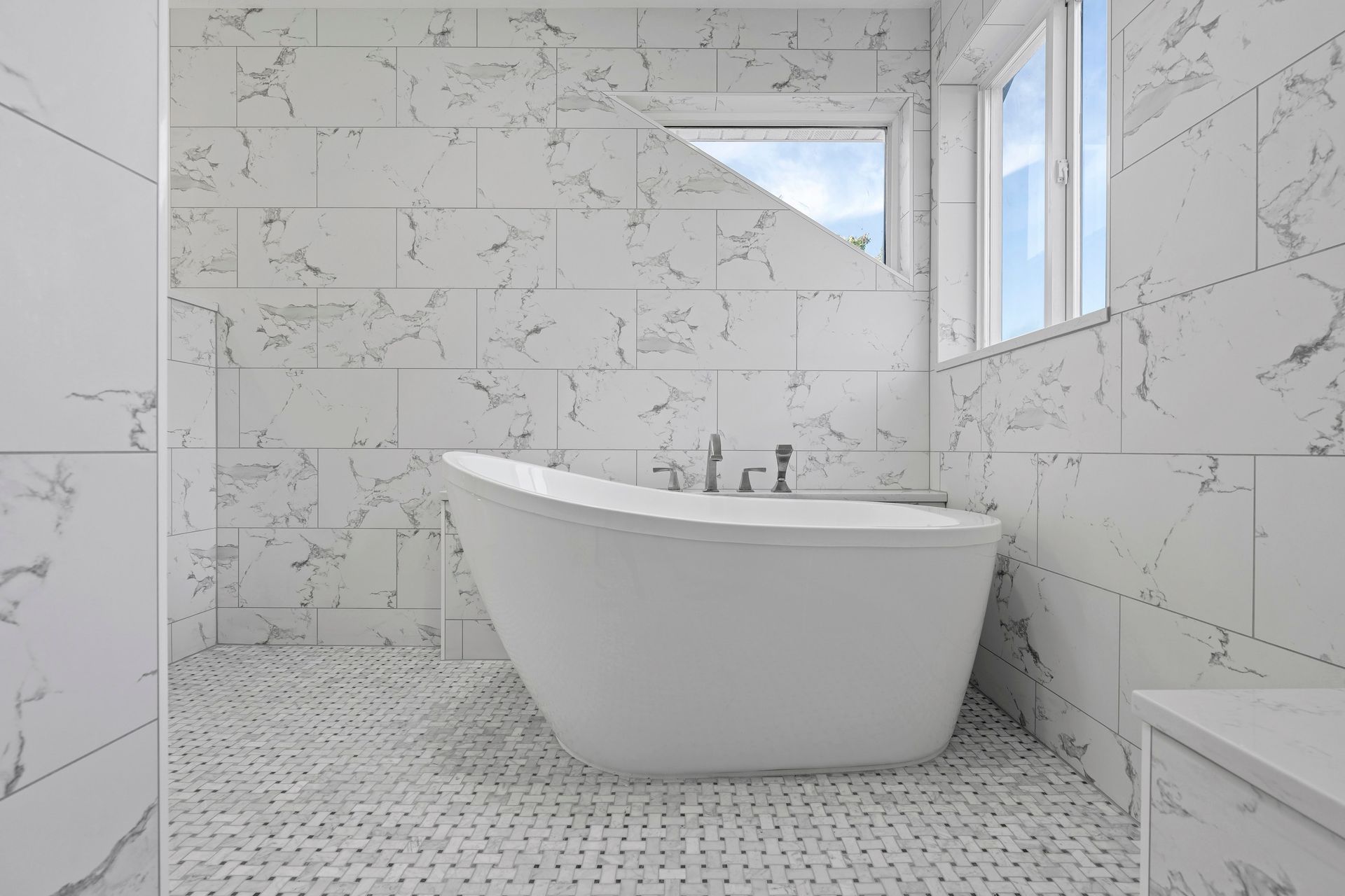 A bathroom with marble tiles and a bathtub.