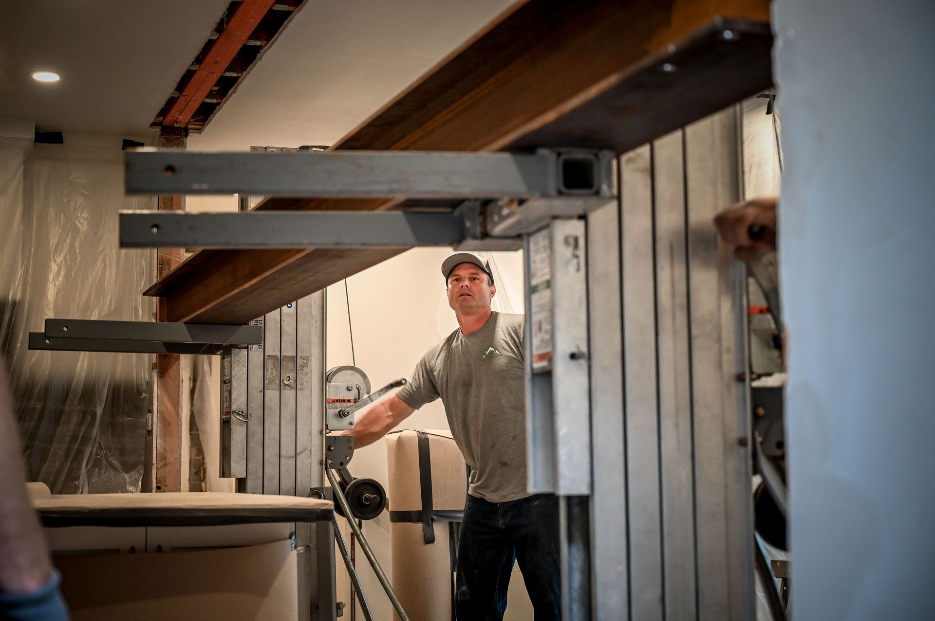 A man is standing under a metal structure in a room.