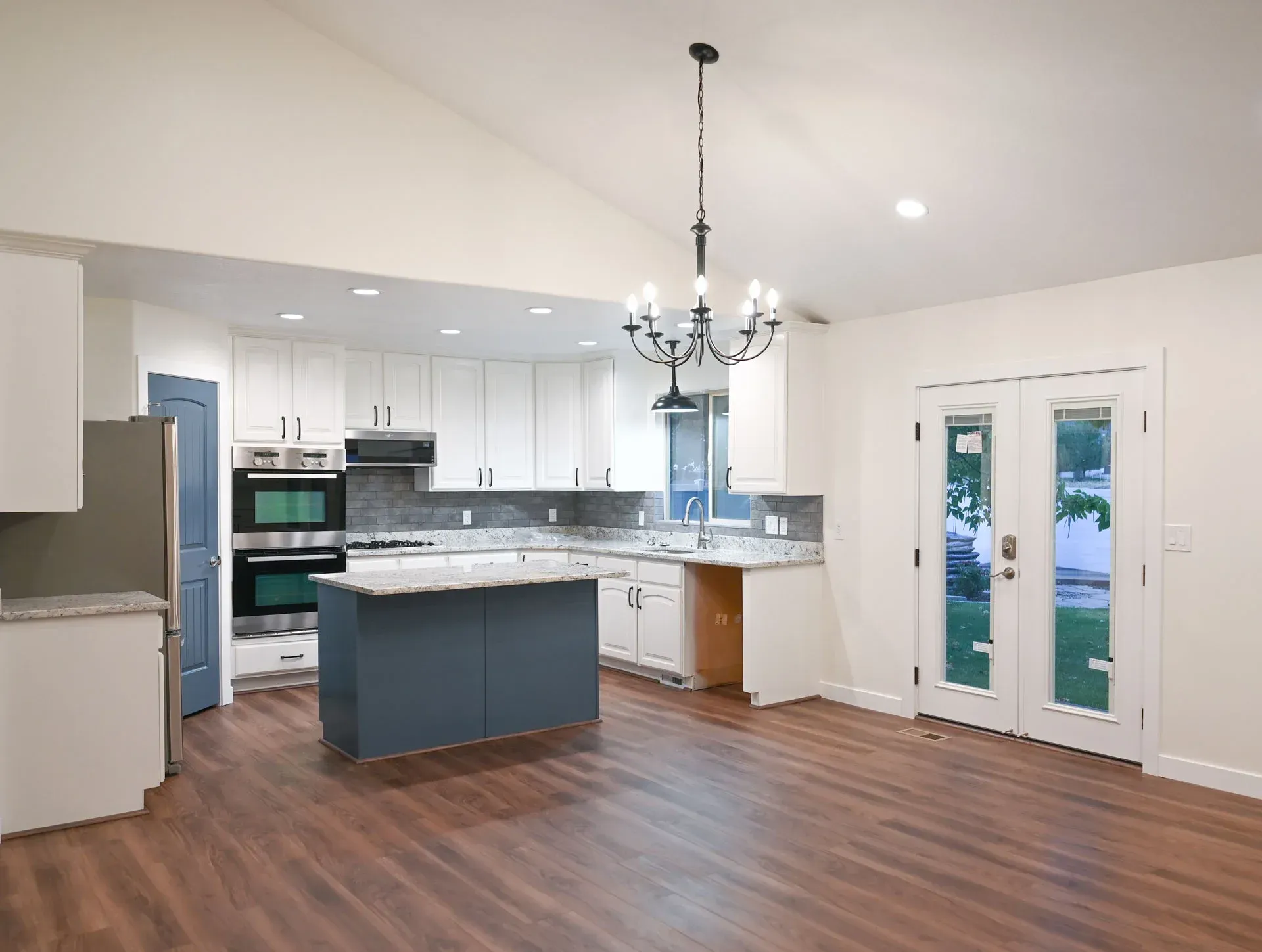 An empty kitchen with white cabinets and a blue island