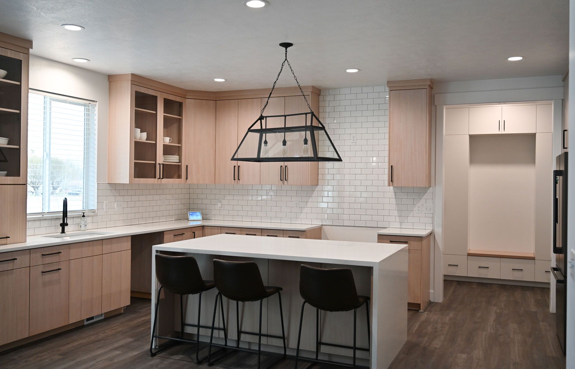 A kitchen with a large island in the middle and a chandelier hanging from the ceiling.