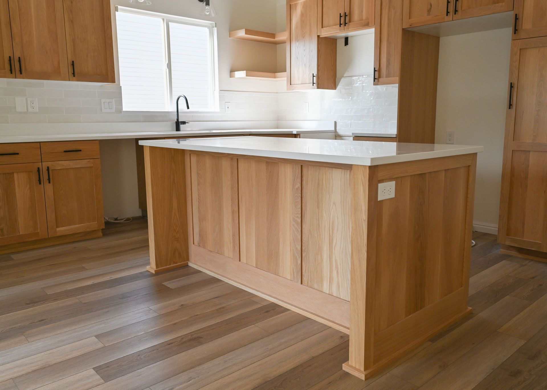 A kitchen with wooden cabinets and a large island in the middle.