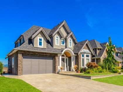 A large house with a gray garage door and a blue sky in the background.