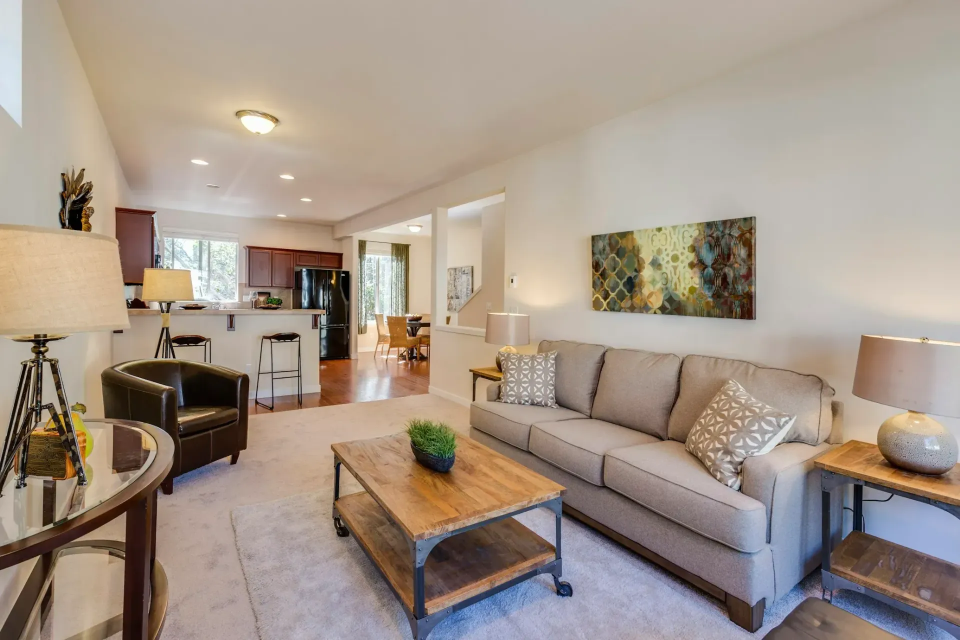 A living room with a couch , chair , coffee table and lamps.