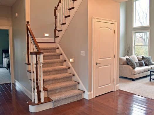 A staircase in a living room with a couch and a door.
