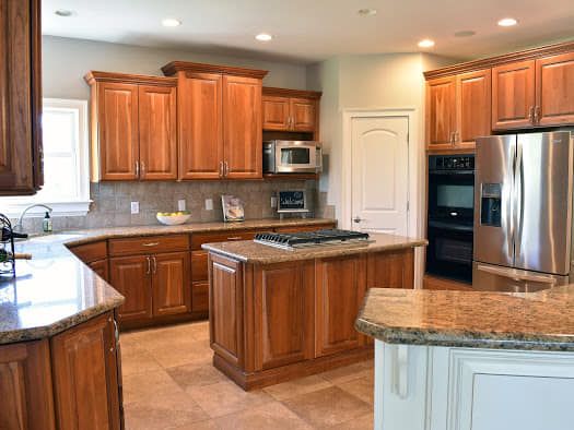 A kitchen with wooden cabinets , granite counter tops , stainless steel appliances and a large island.
