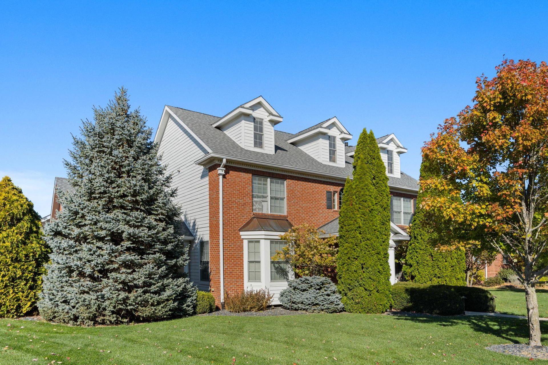A large house with a gray roof and white garage doors