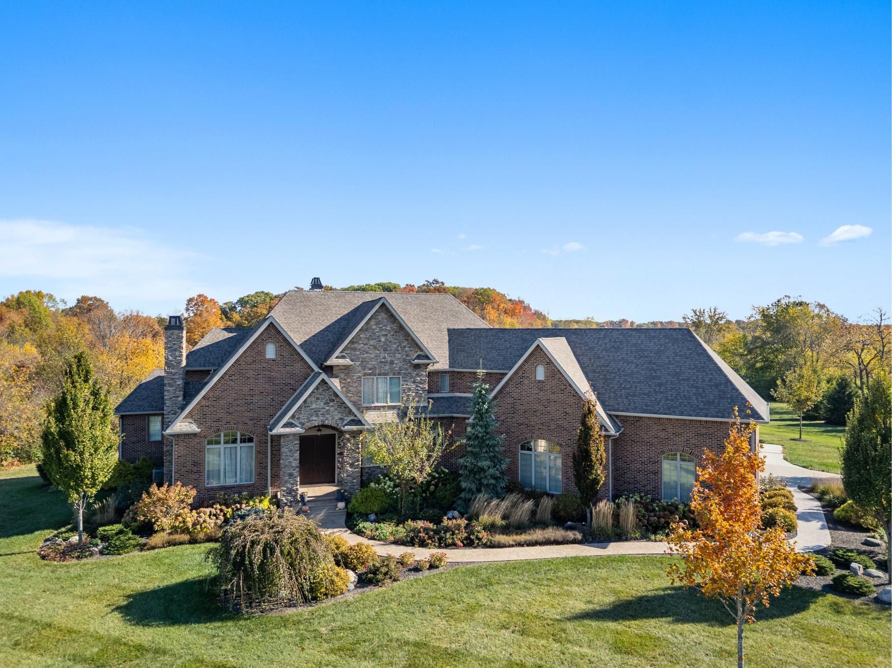 A man is kneeling on the roof of a white house with black windows.