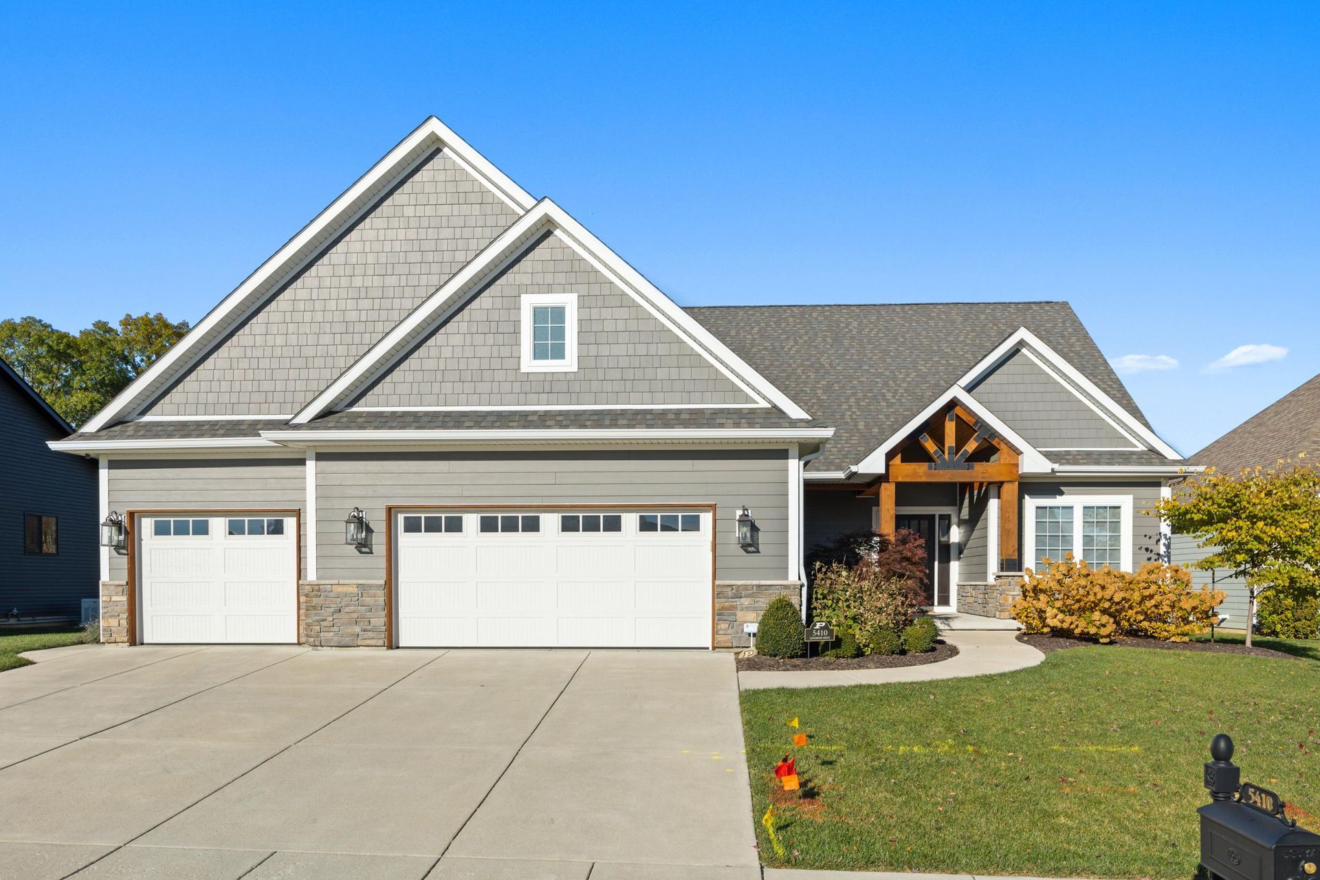 A large house with a large driveway and a lush green lawn.