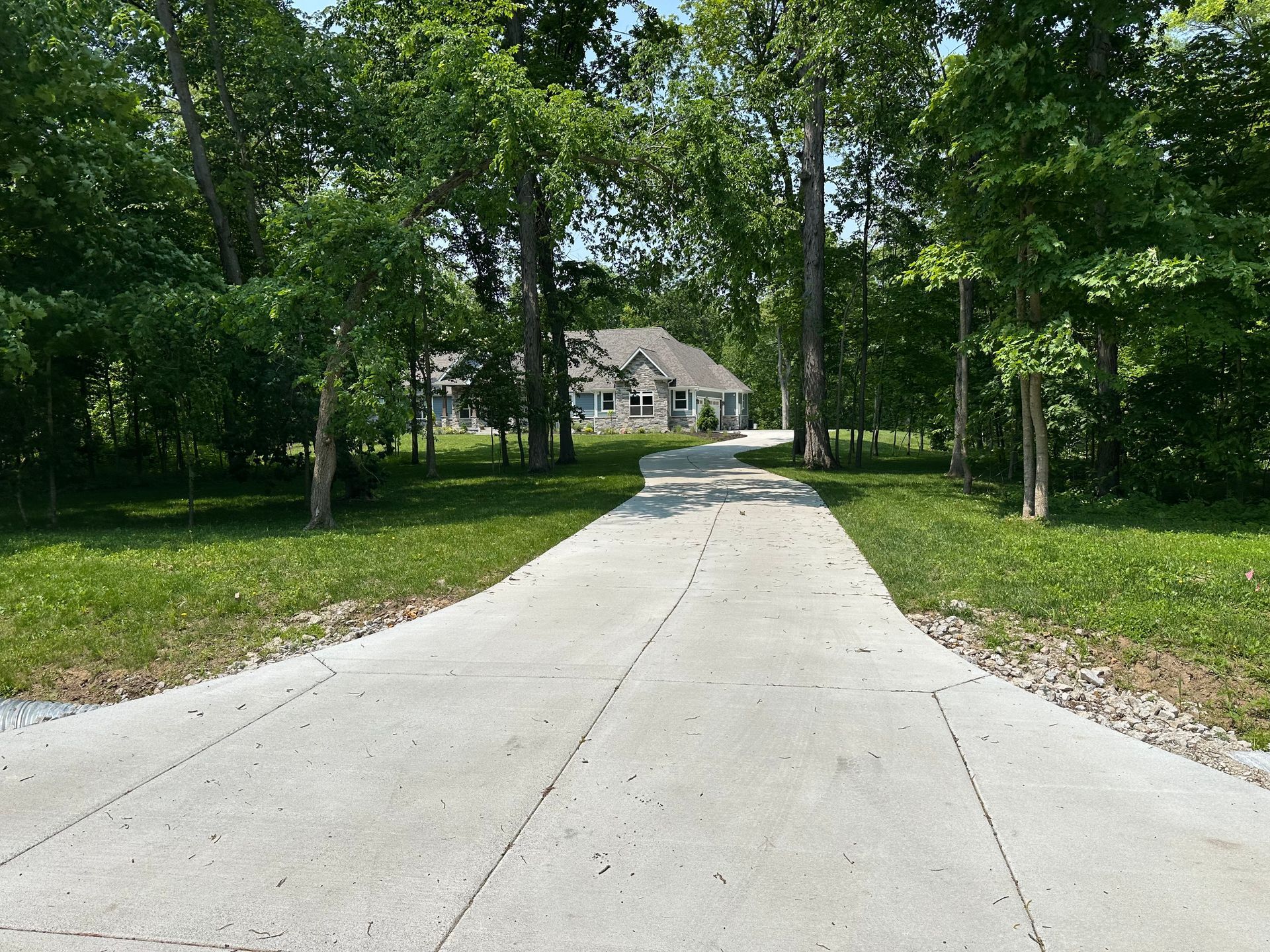 A large house with a large driveway and a lush green lawn.