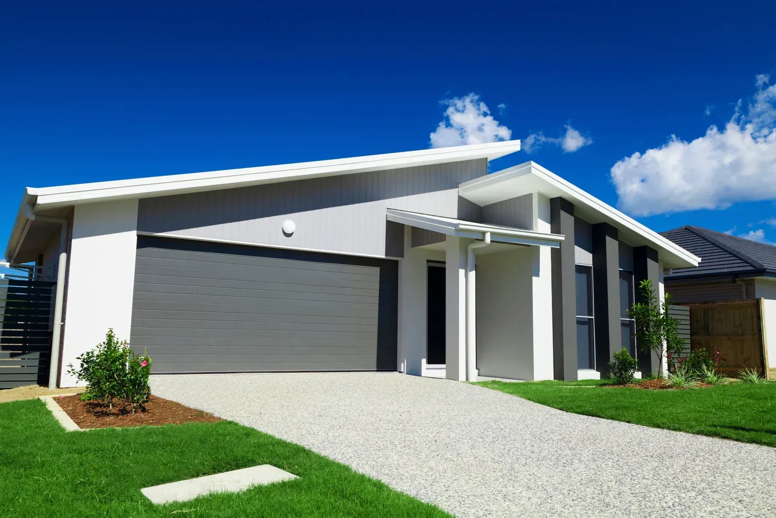 A white house with a gray garage door and a driveway