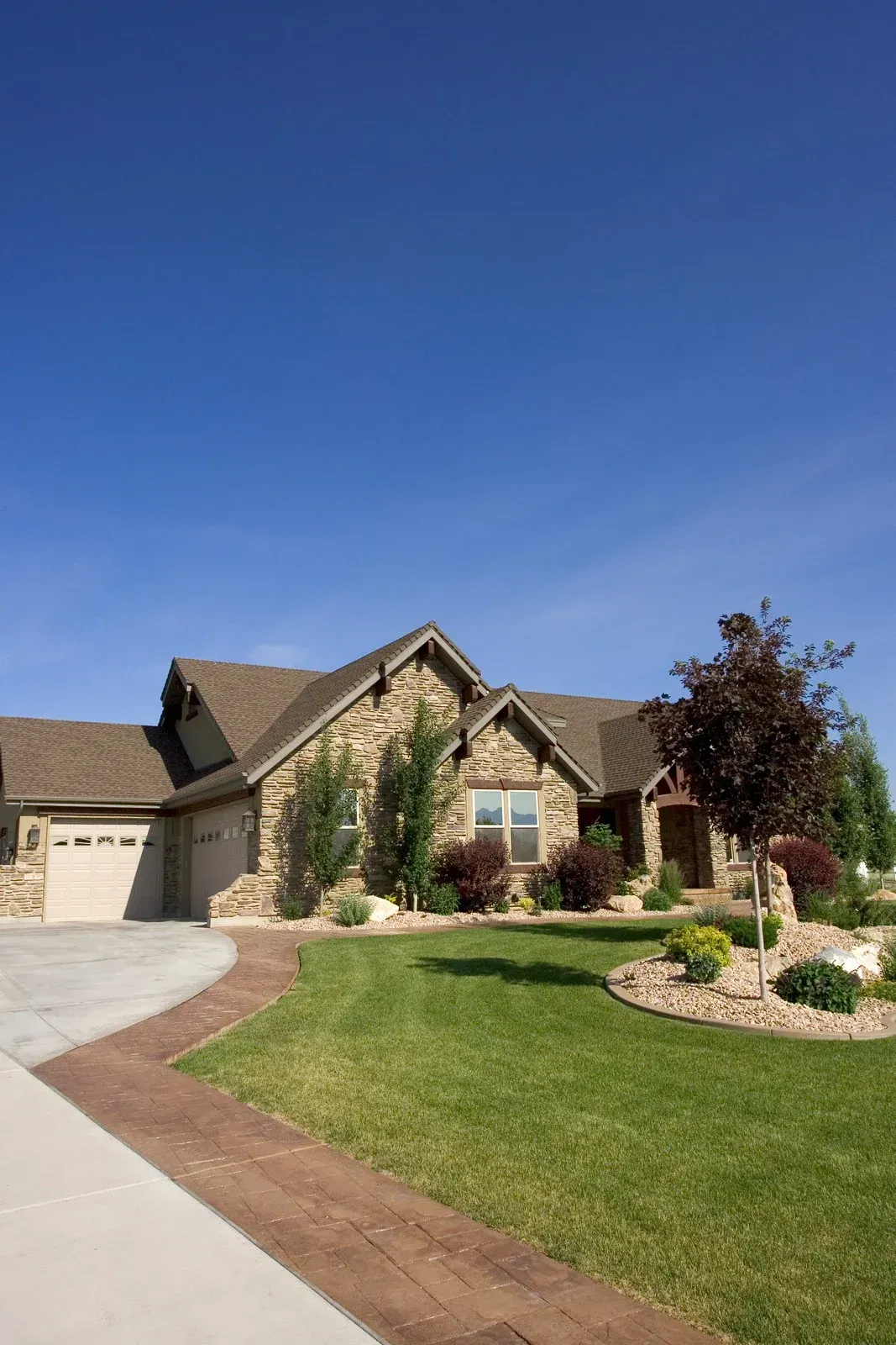 A large house with a large driveway and a lush green lawn.