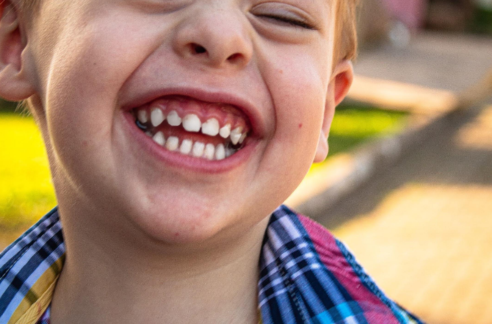 A close up of a young boy smiling with his eyes closed.