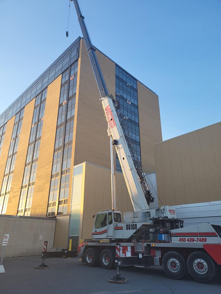 Une grande grue est garée devant un grand bâtiment