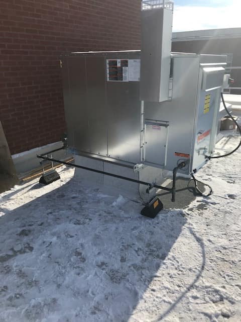 Une grande boîte en métal repose dans la neige devant un bâtiment en brique.