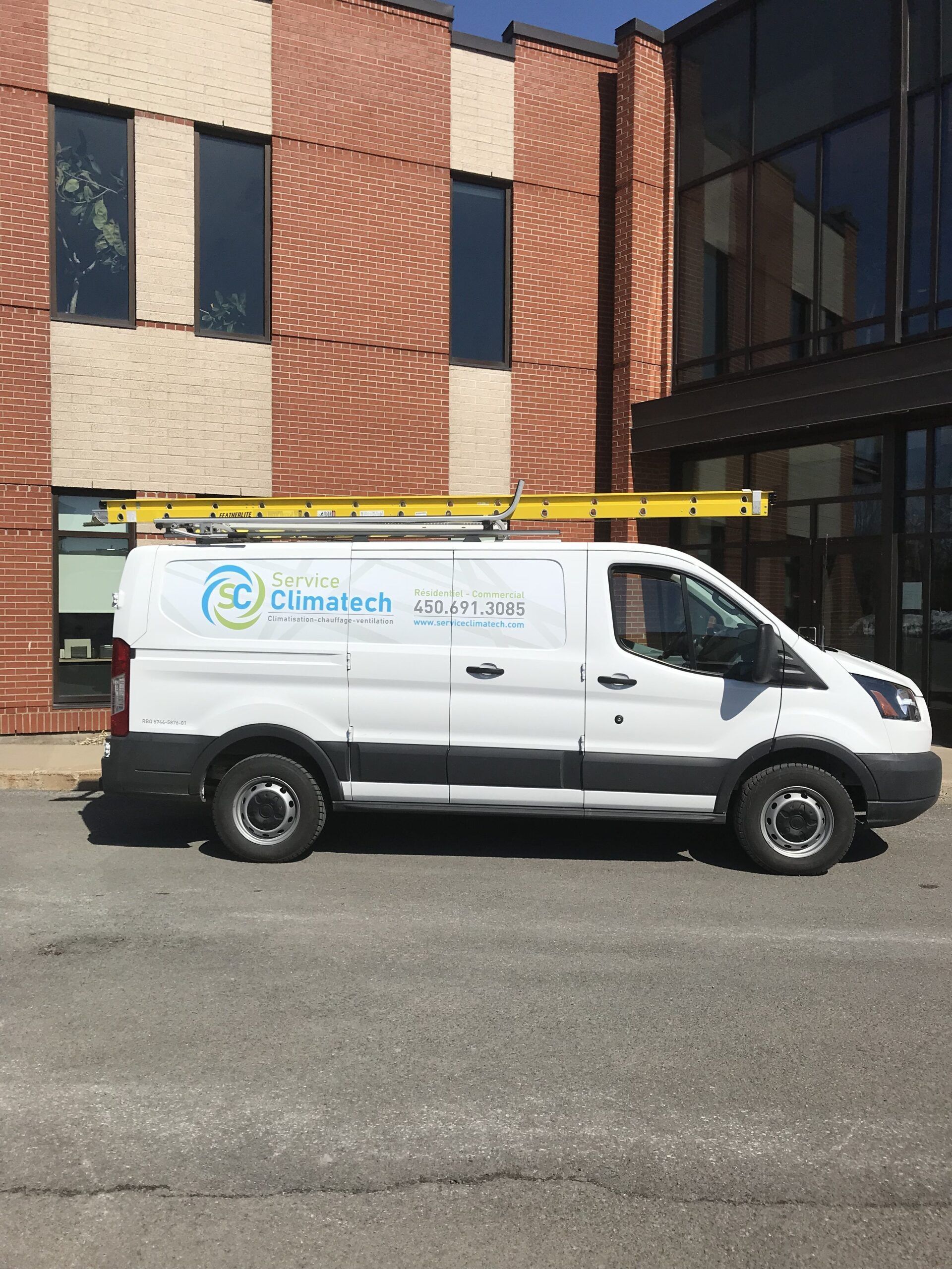 Une camionnette blanche est garée devant un bâtiment en brique