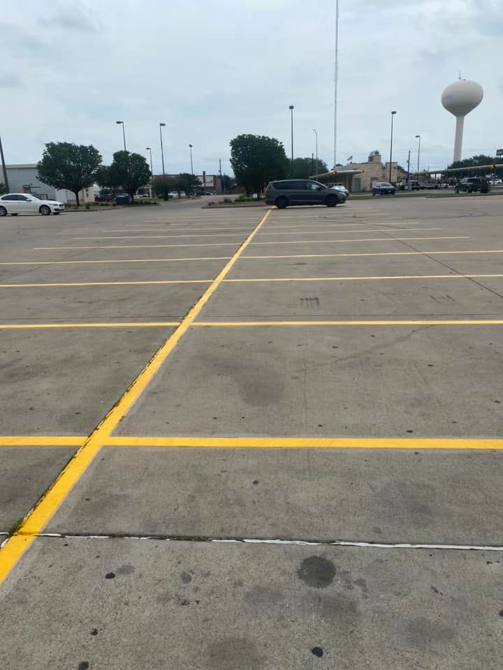 A parking lot with yellow lines and a water tower in the background