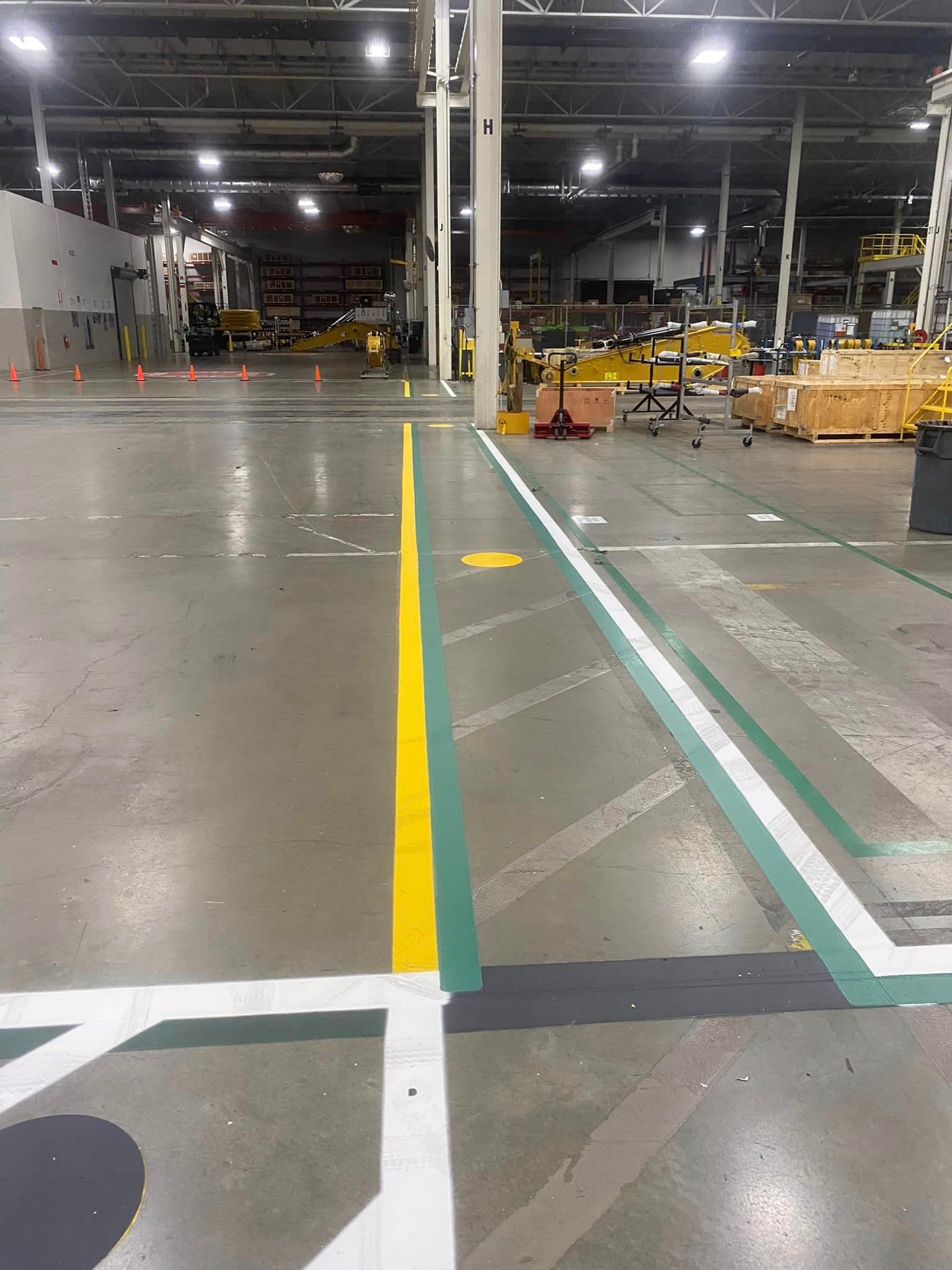 A large warehouse with a yellow and green line on the floor.