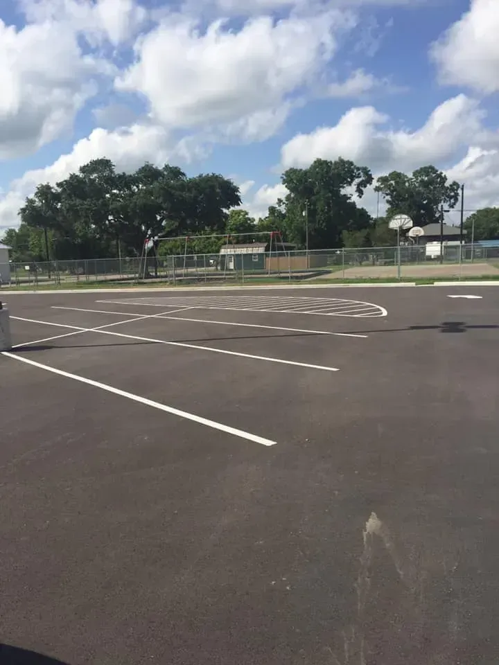 A parking lot with a basketball court in the background