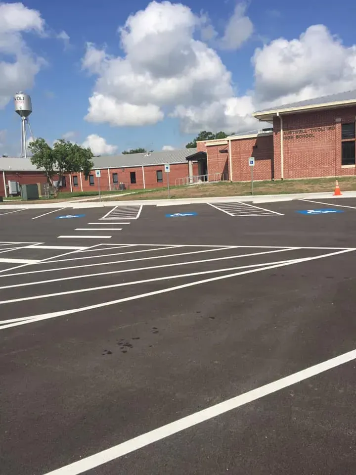 A parking lot in front of a brick building with a water tower in the background