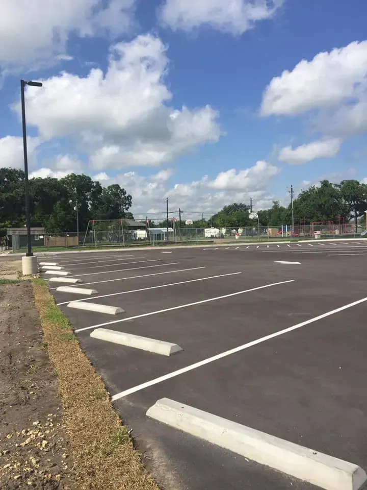 An empty parking lot on a sunny day with trees in the background