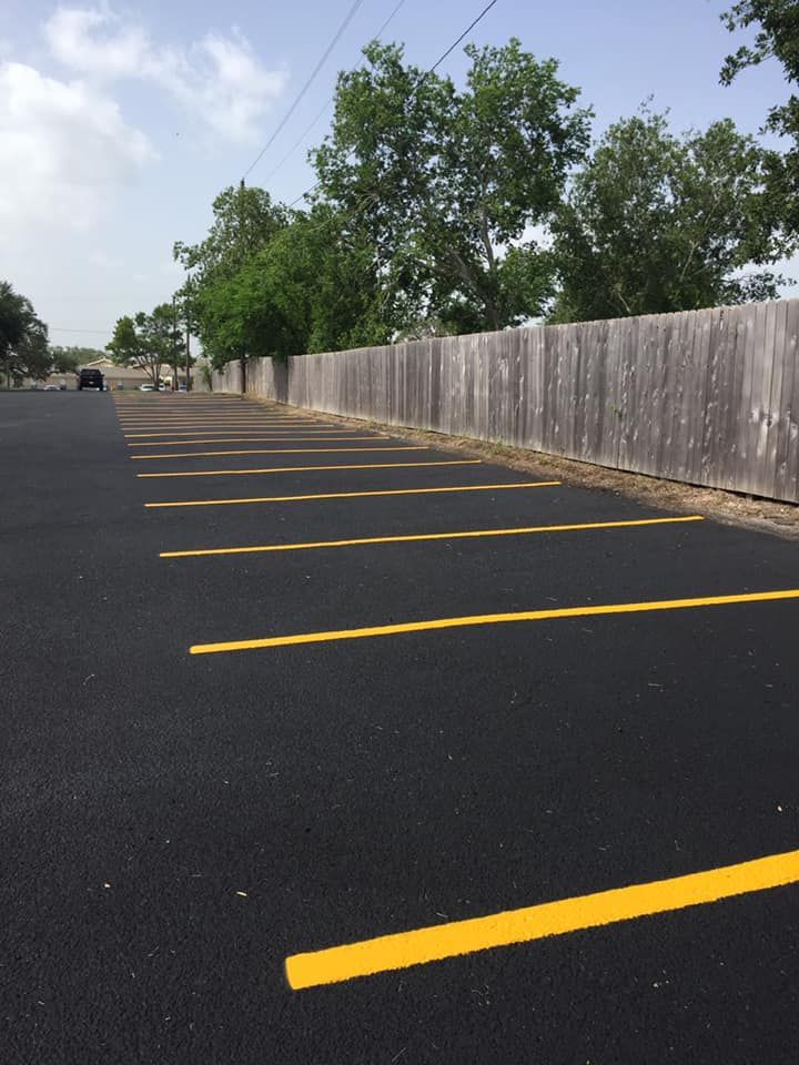 A parking lot with yellow lines and a wooden fence