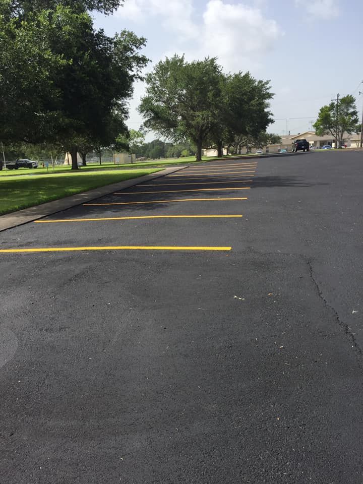 A parking lot with yellow lines and trees in the background