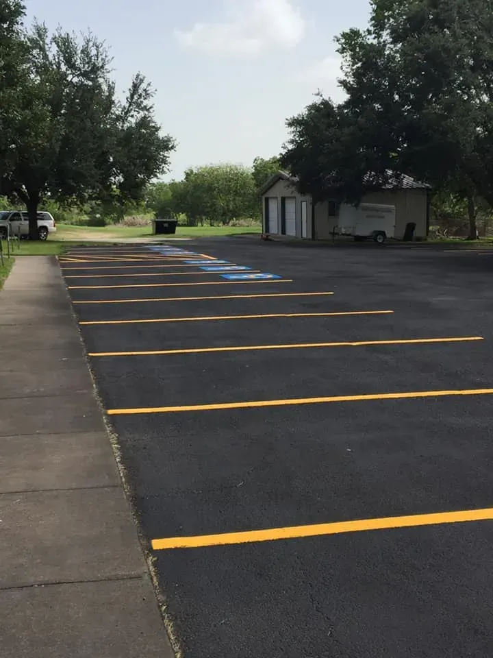 A parking lot with yellow lines and a small building in the background