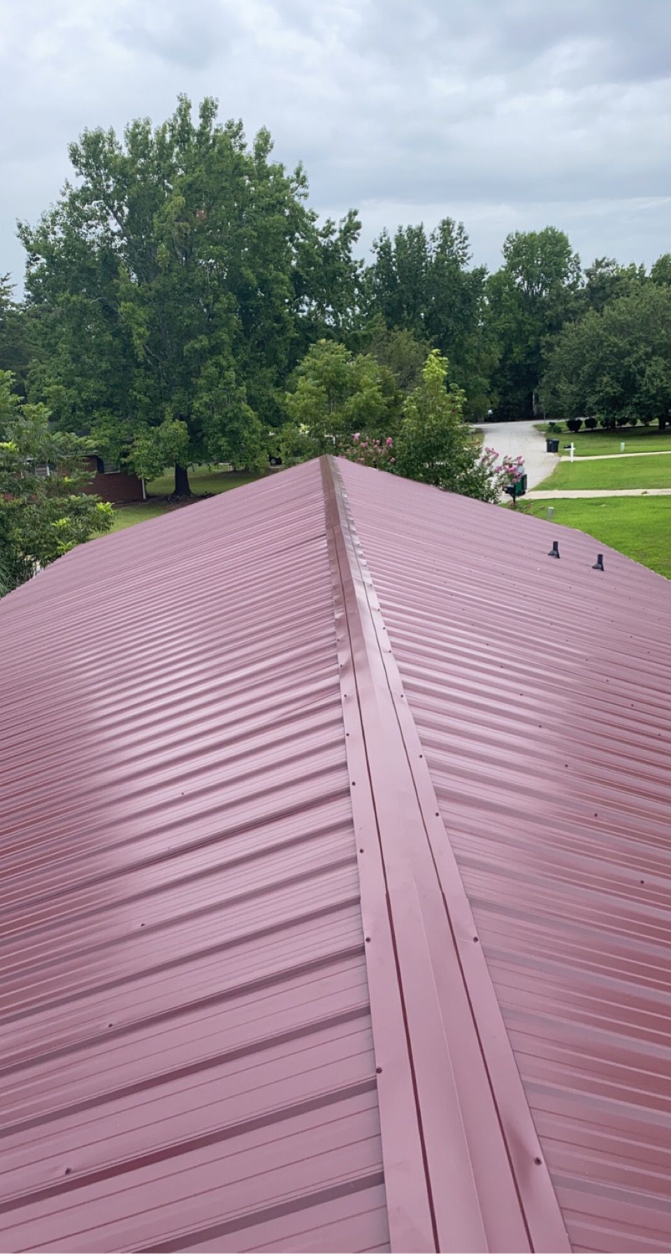 An aerial view of a suburban neighborhood with houses, manicured lawns, and paved streets on a sunny day.