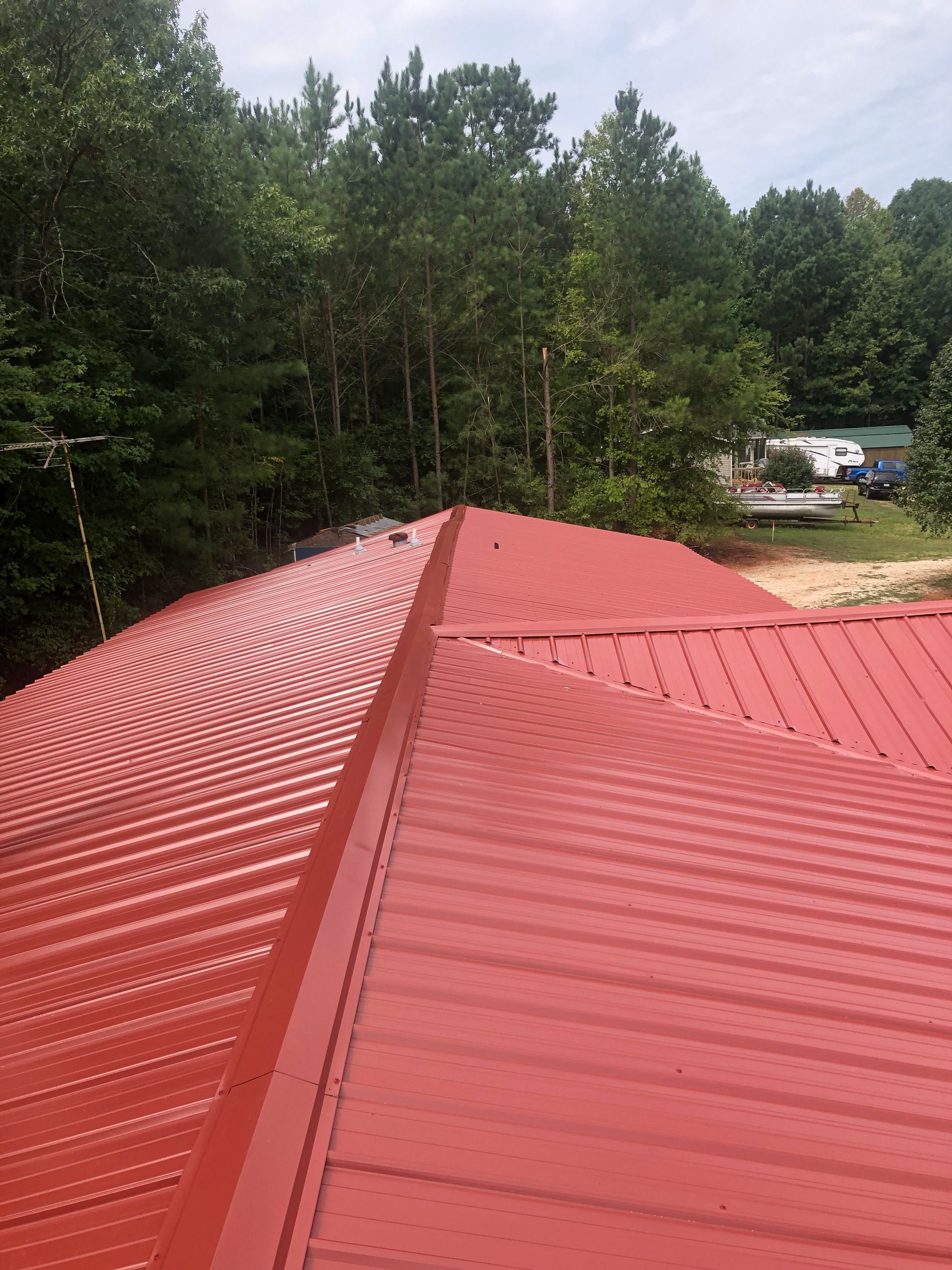 A worker in protective gloves repairing shingles on a sloped roof with a hammer and nails nearby.