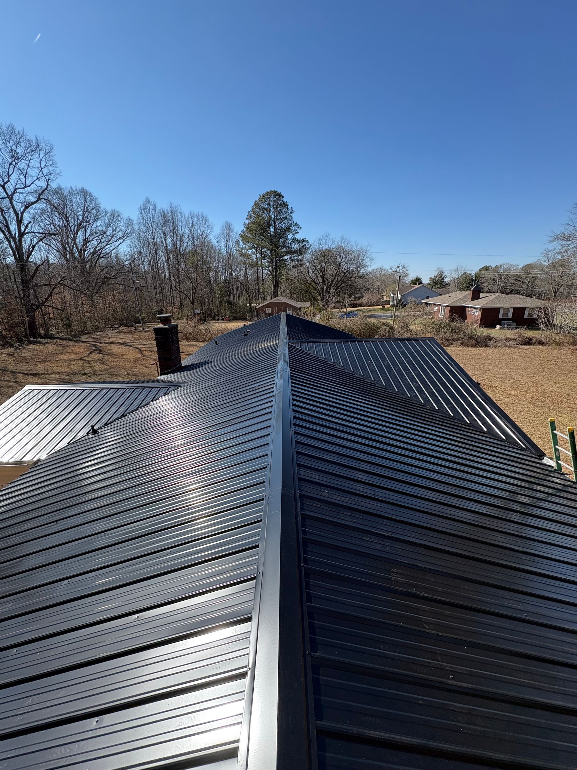 A group of people standing outside a house under construction, looking at a set of blueprints together.