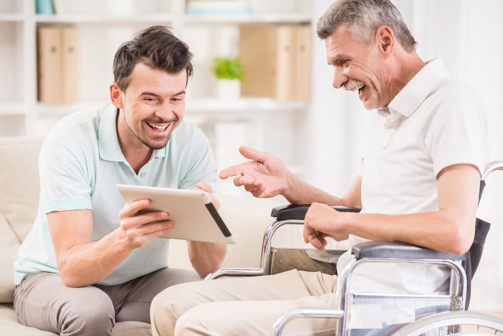 Smiling Man Having Fun With His Father In Wheelchair — Aged Care Service in Kilgra, NSW
