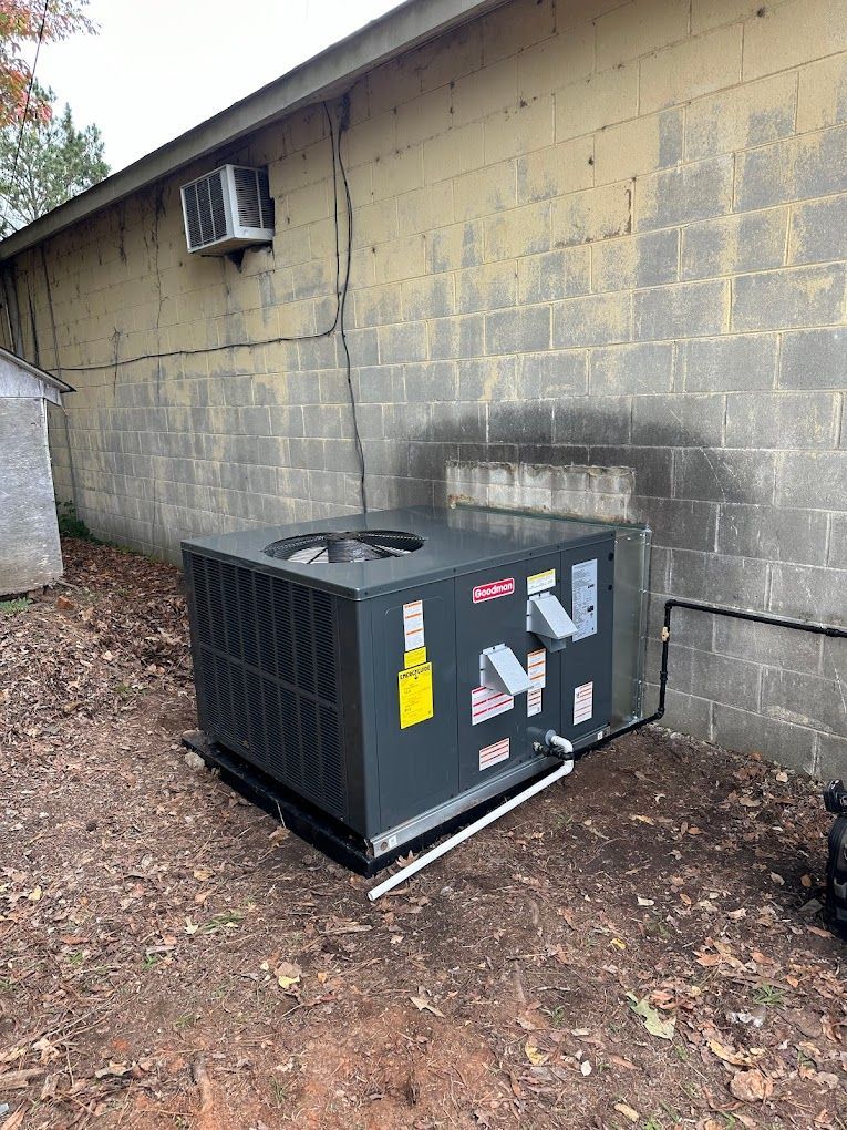 A large air conditioner is sitting outside of a brick building.