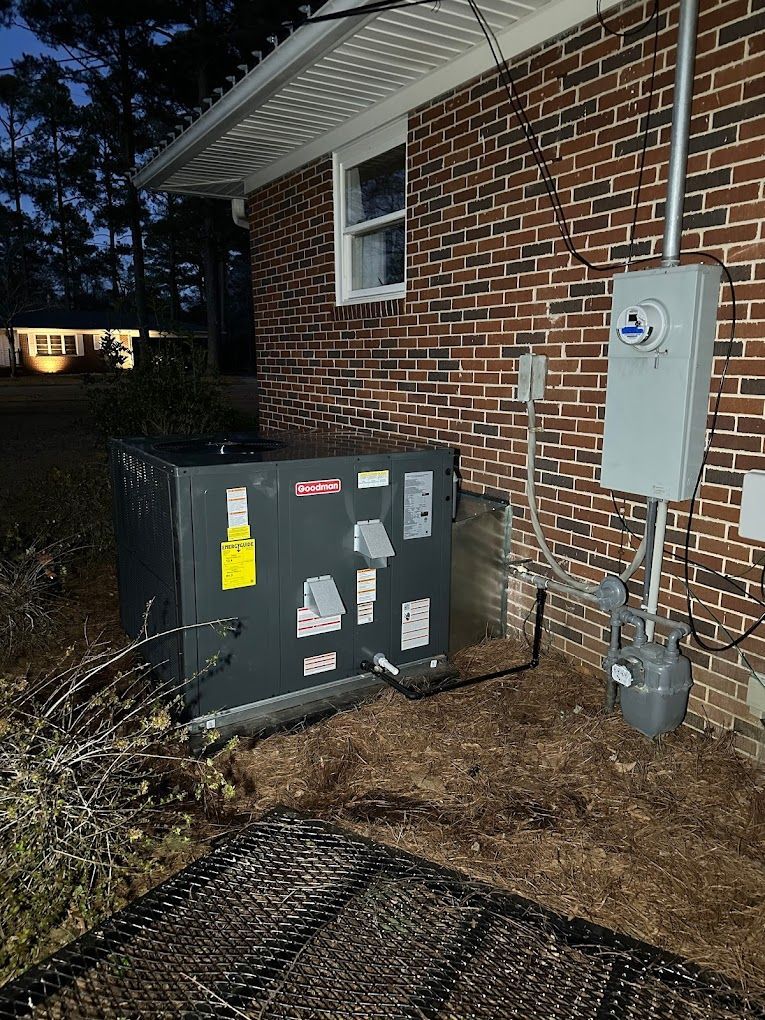 An air conditioner is sitting on the side of a brick house.