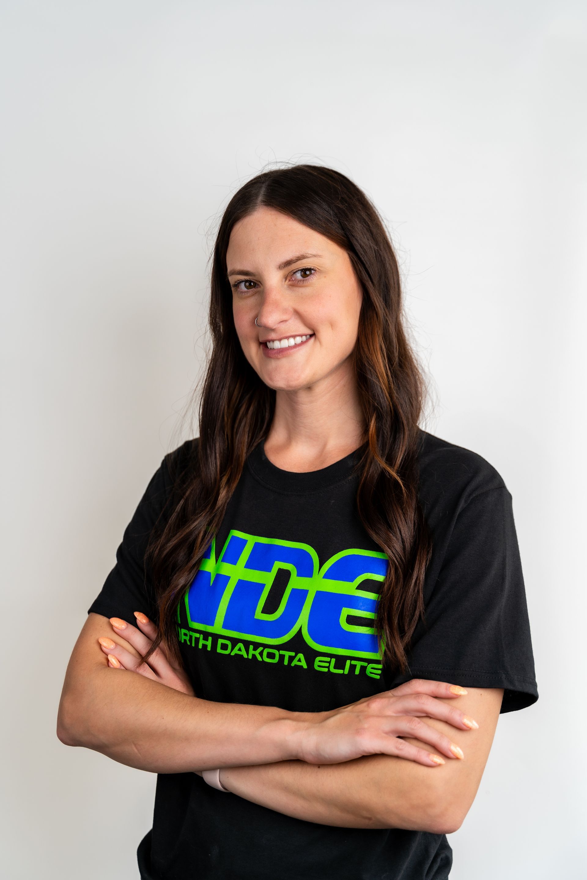 A woman is sitting in a chair wearing a black shirt with the letter d on it.