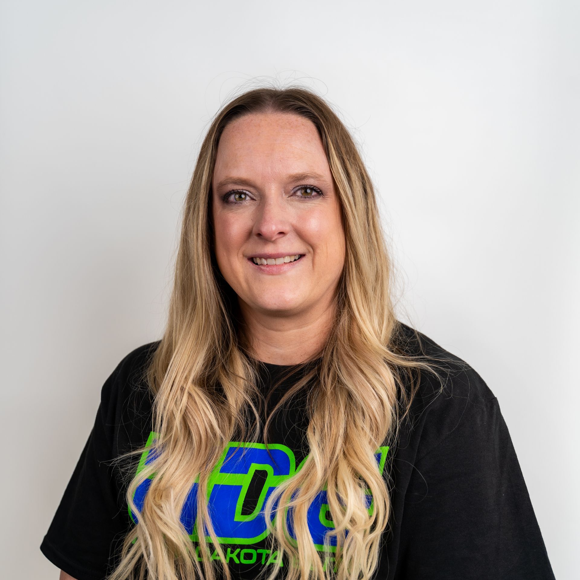 A woman is sitting in a chair wearing a north dakota elite sweatshirt.