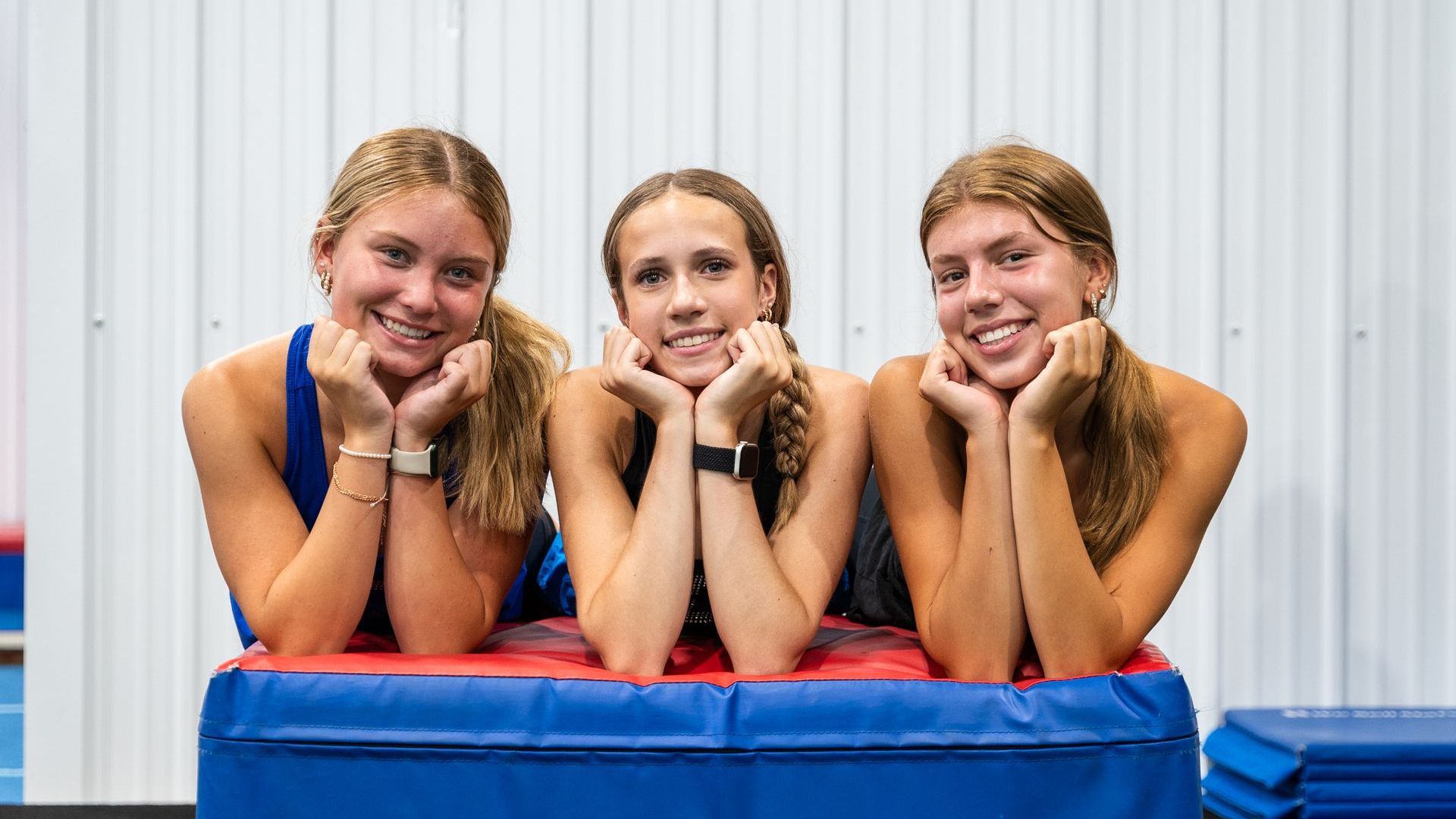 Three young girls are doing exercises on a white background.