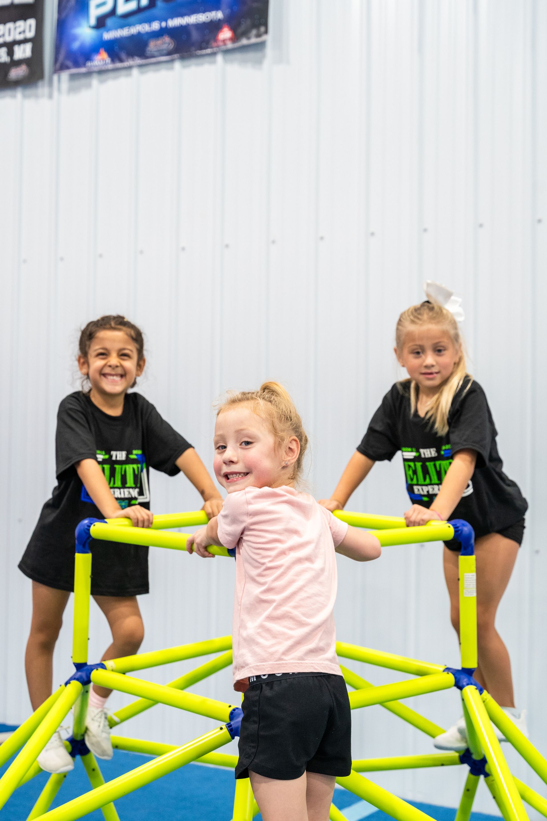 A woman is helping a young girl do a handstand on a mat in a gym.